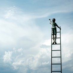 Child on a ladder reaching up into the sky